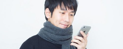 恋人からのメッセージを確認するマフラーを巻いた男性