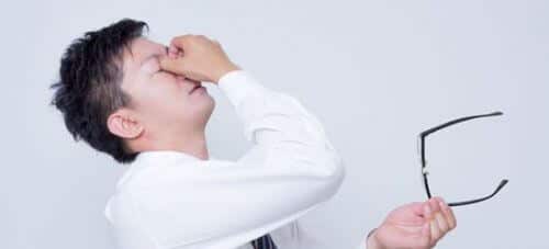眼球疲労で目をおさえるビジネスマン