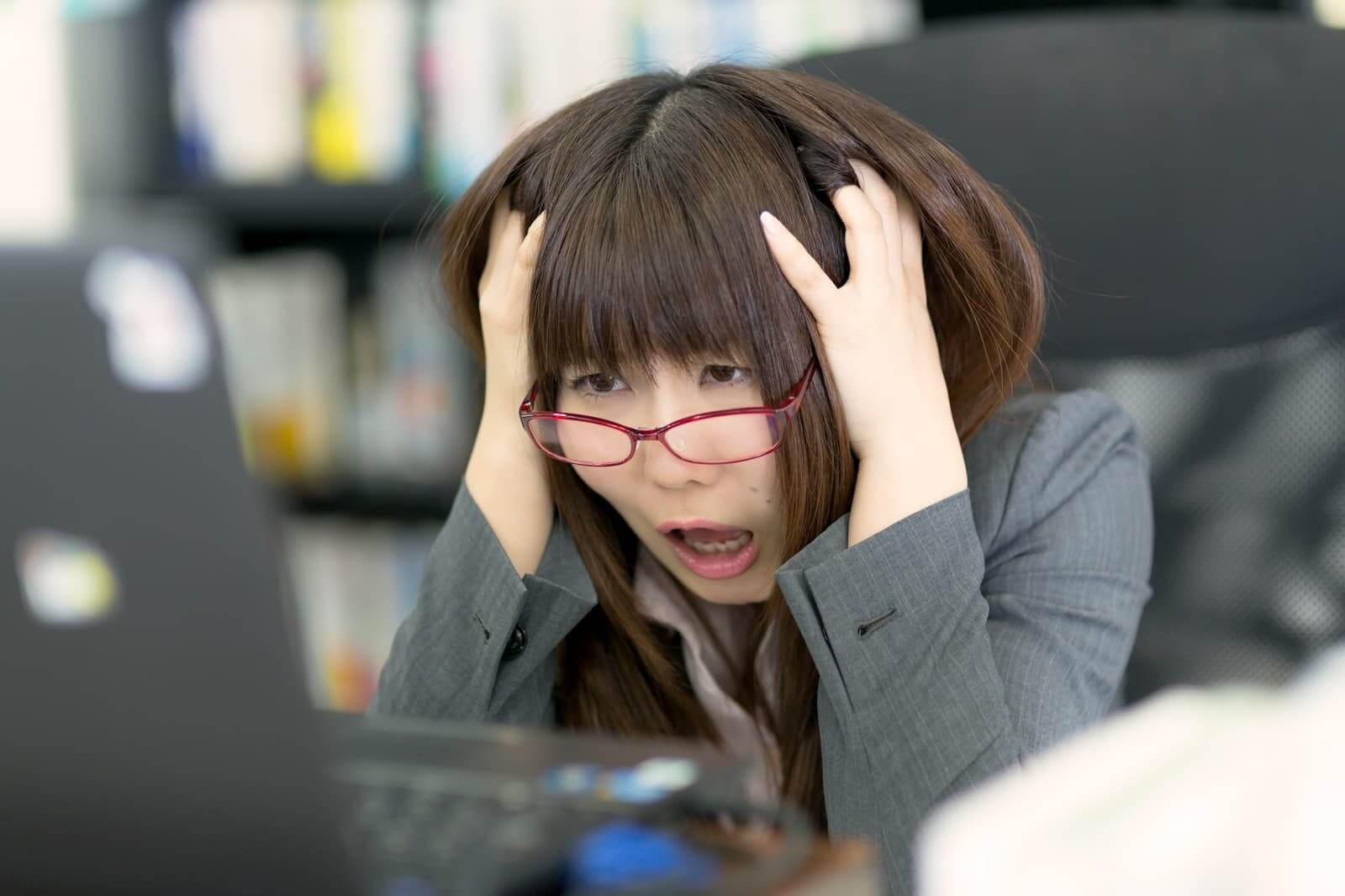 PCモニターを見て頭を抱えるOL