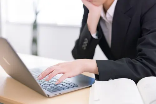 頬杖をつきながらキーボードに手を添える女性