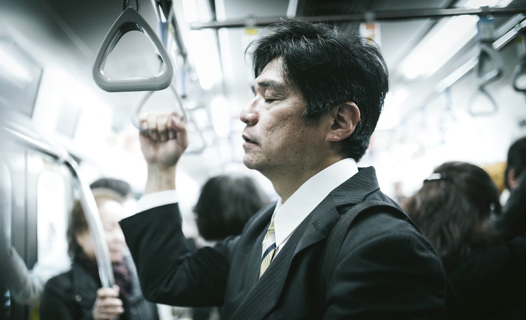 睡眠不足で電車の中で、立ったまま寝る中年男性