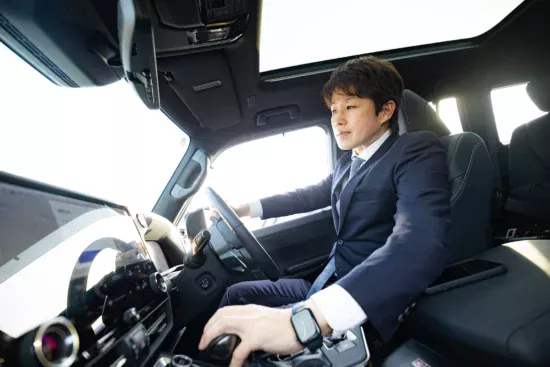 運転席でハンドルを握るスーツ姿のビジネスマン