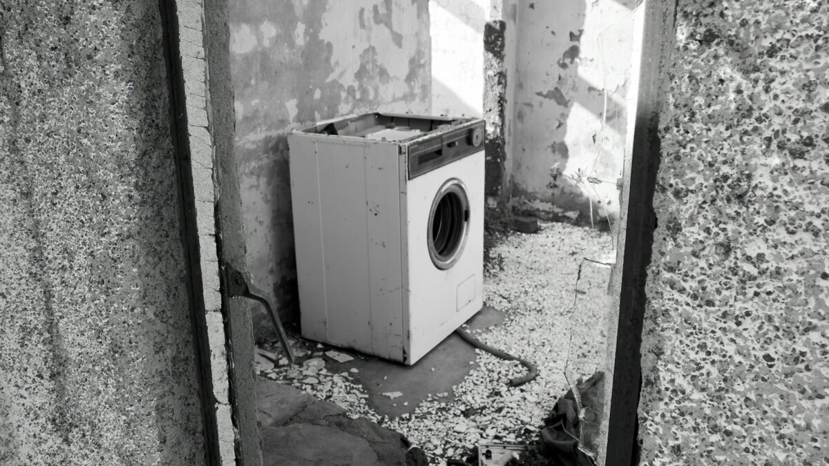 廃屋のコンクリートの床に置き去りにされた古いドラム式洗濯機